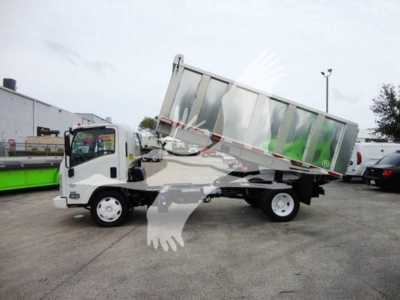 Isuzu NQR dump truck side view with tilting cargo bed in raised position showing truck cab and rear wheels.