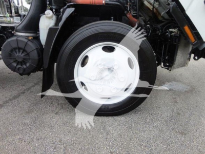Isuzu NQR front wheel and suspension area with truck components visible.