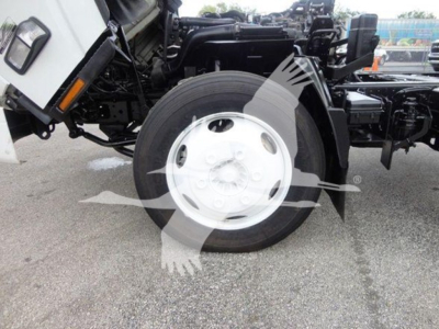 Isuzu NQR truck front wheel area showing a large white steel wheel and exposed suspension components; faint watermark logo across the image.