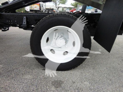 Isuzu dump truck chassis showing front wheel and tire; white steel wheel; part of chassis and mud flap visible.