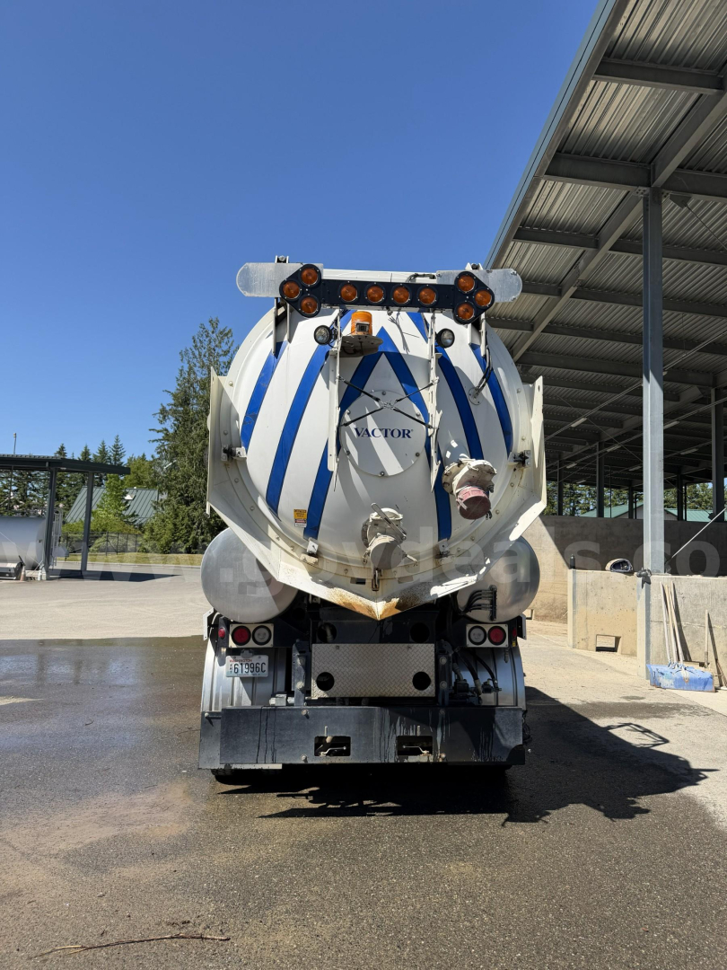 Rear view of a 2003 Volvo VHD vacuum truck with a striped white and blue tank, dual rear lights, and a metal platform under the tank.