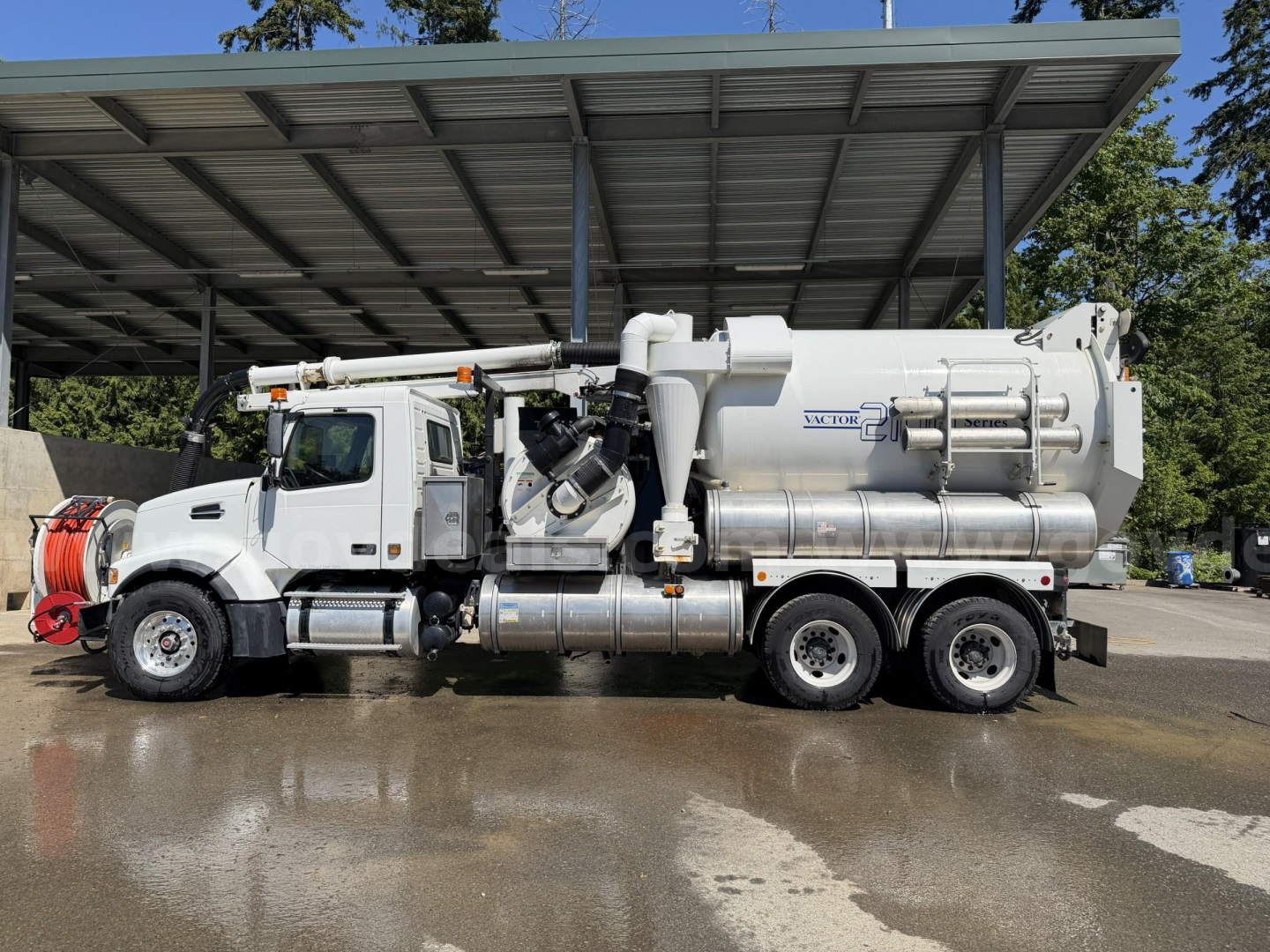 Volvo VHD vacuum truck side view showing large cylindrical tank and vacuum hoses under a metal canopy.