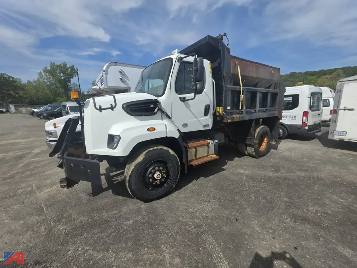 Dump truck with dumping bed, white Freightliner 108SD, front view showing cab and side of bed, indicating VIN 1FVAG5BS9DHFA4388 in a used truck lot.