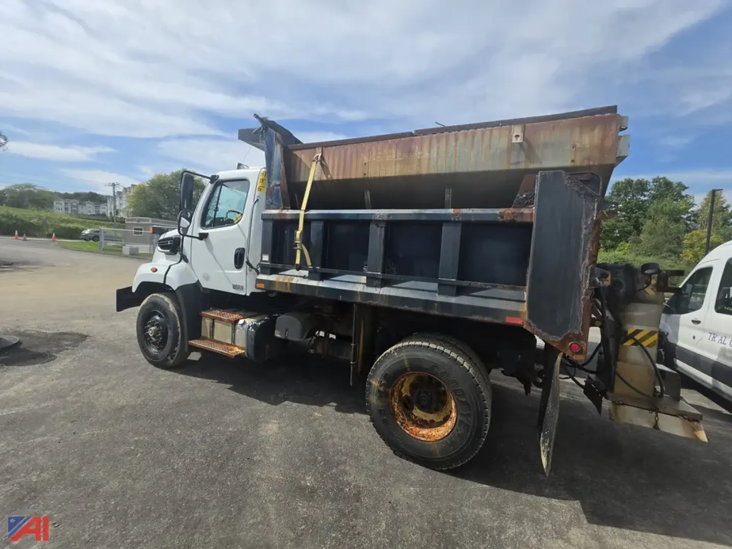 Dump truck side view showing open-top dump bed, white cab, black underbody, and rusted rear wheels on a Freightliner 108SD.