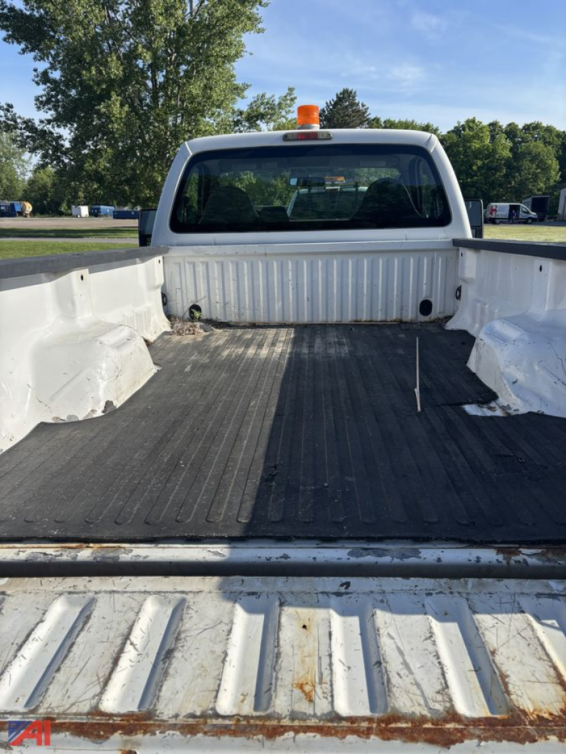 Truck bed of a 2010 Ford F350 pickup showing a white crew cab with a cargo bed and an orange warning beacon on top.