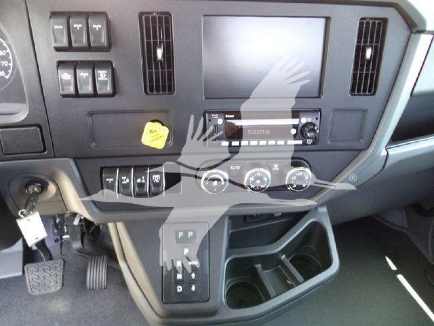 Dashboard of a Peterbilt truck with a central touchscreen, climate controls, gear shifter, and various switches.