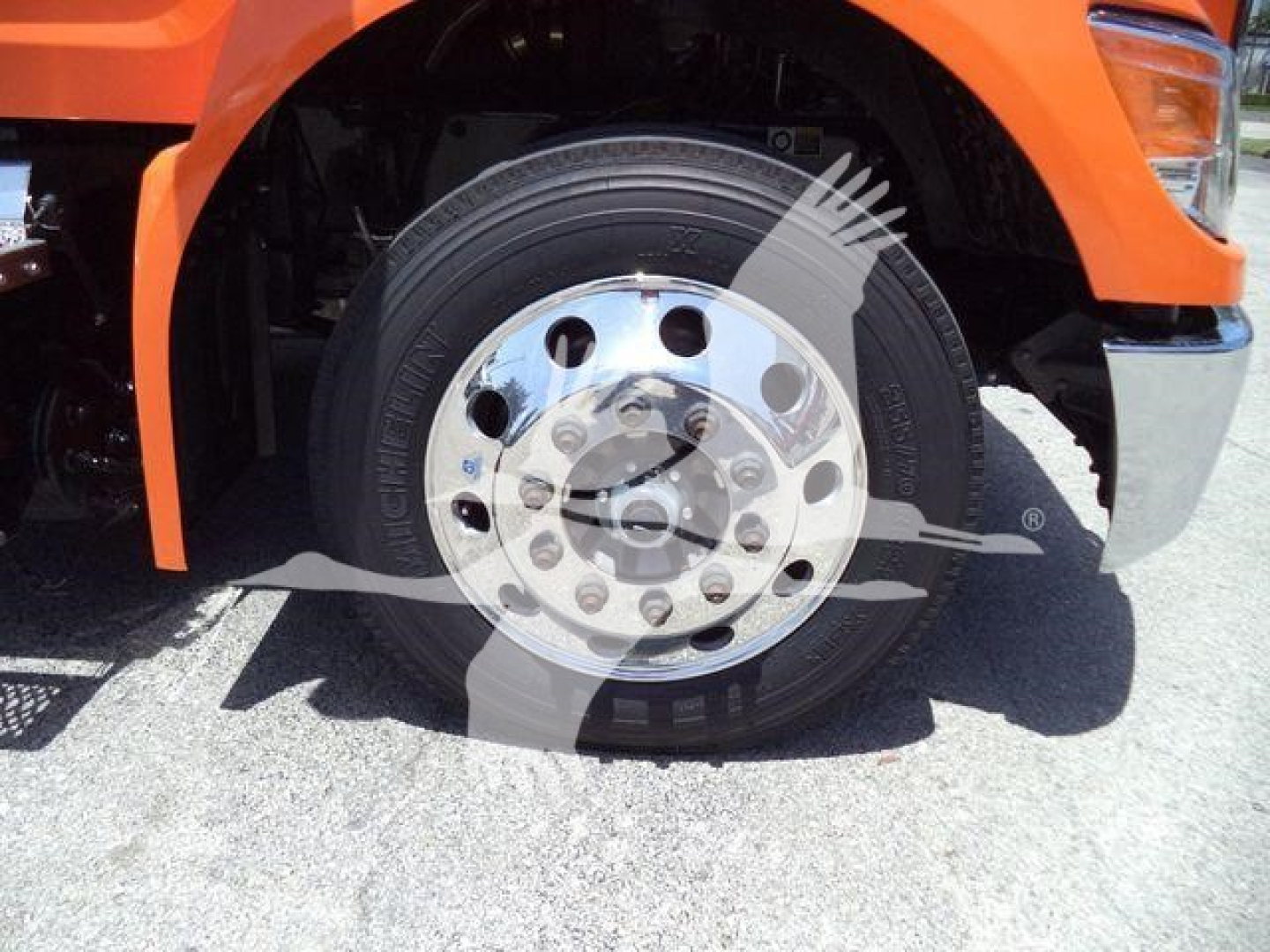 Front wheel and tire of a Peterbilt truck showing steel wheel and hub, orange fender in view.