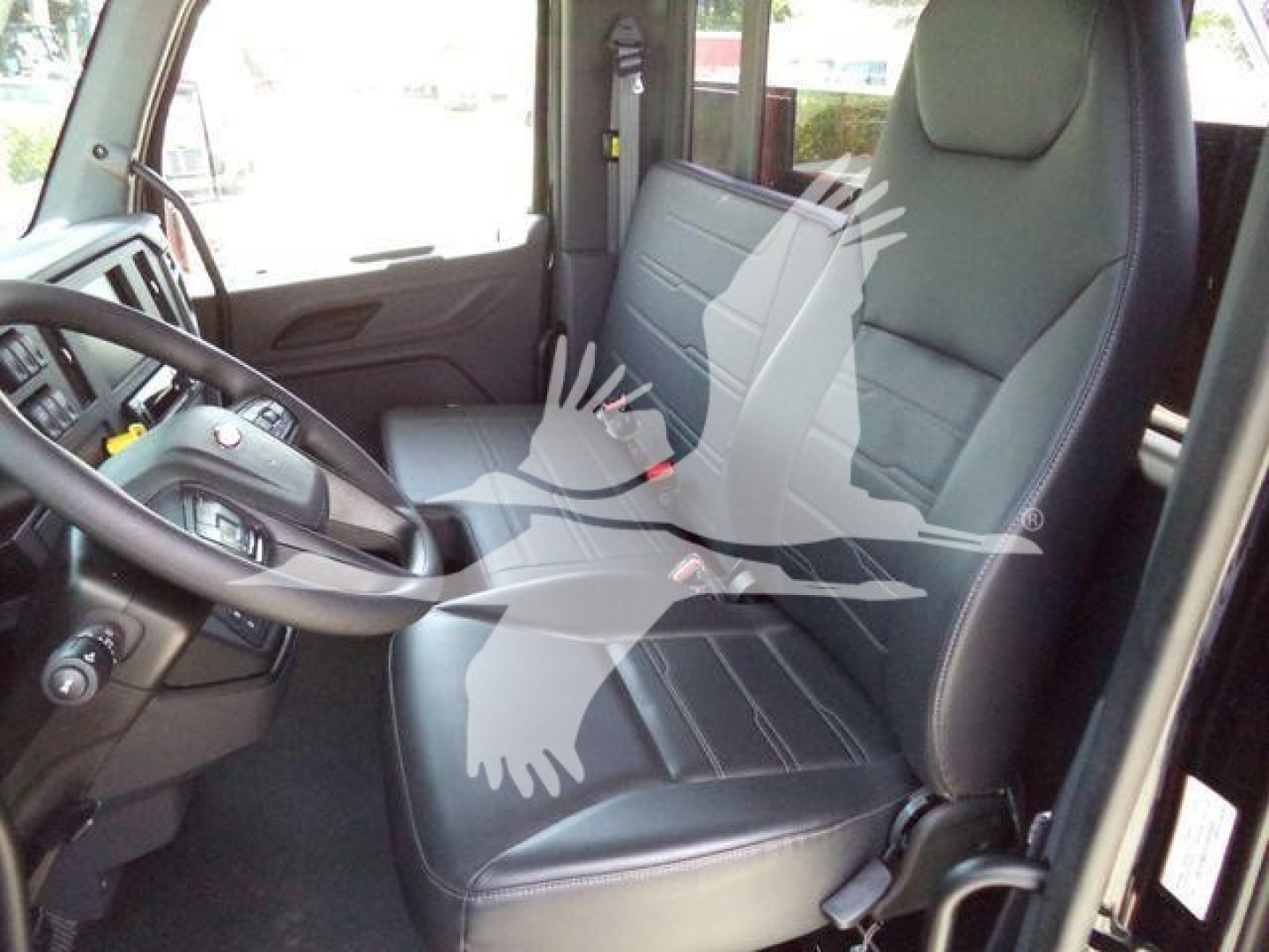 Peterbilt truck interior showing driver and passenger seats and steering wheel, black leather-like upholstery, side door panel, dashboard area.
