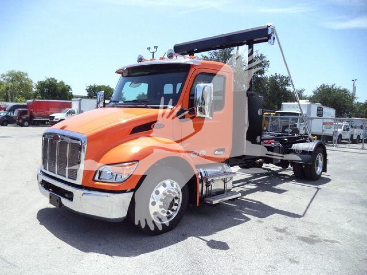 Peterbilt 536 cab with orange front and tan sleeper, view of chassis and hydraulic boom hoist in raised position, front grille and headlights visible.