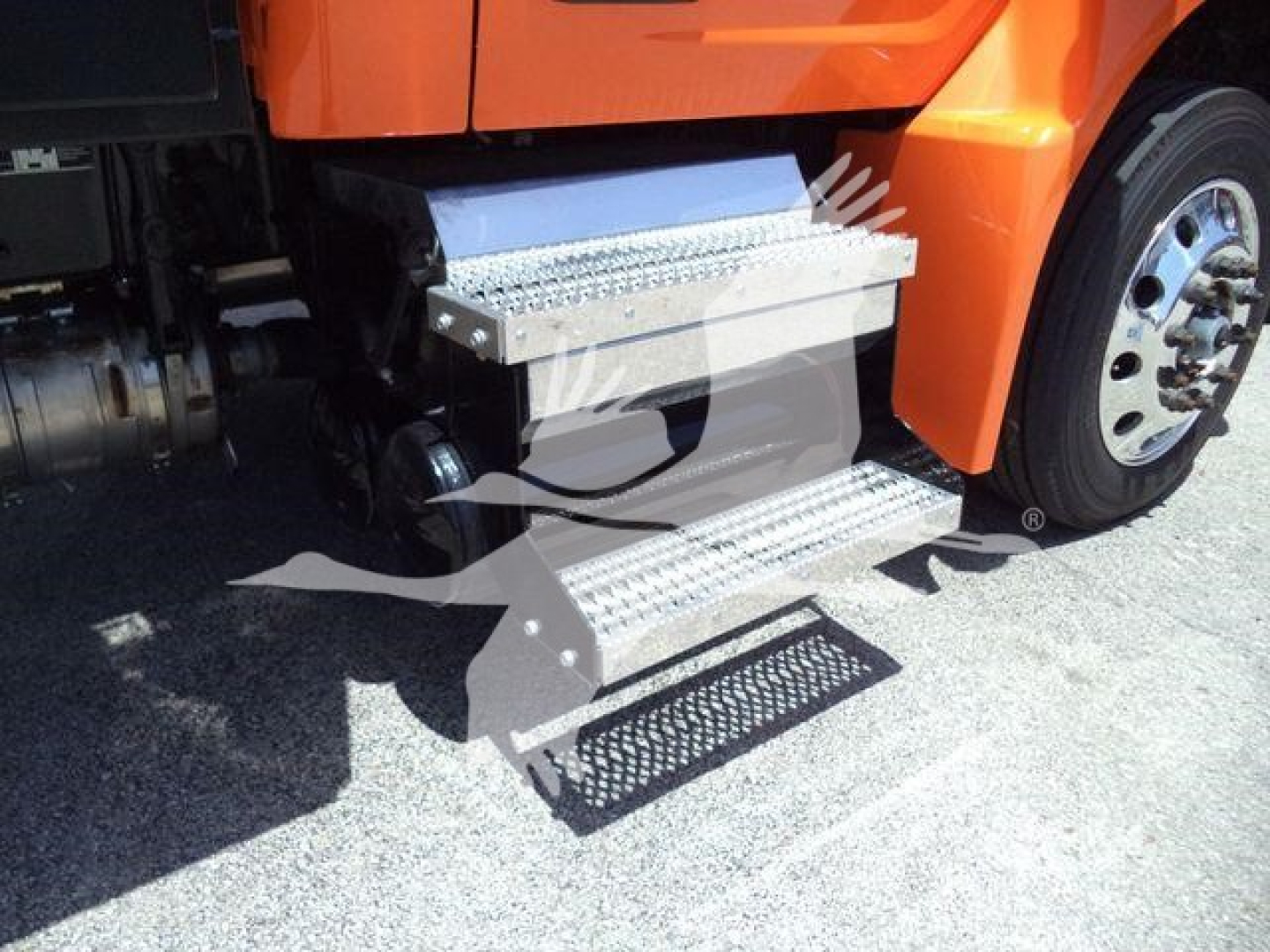 Peterbilt 536 truck side view showing aluminum drop steps and undercab access with perforated metal tread; portion of front wheel visible.