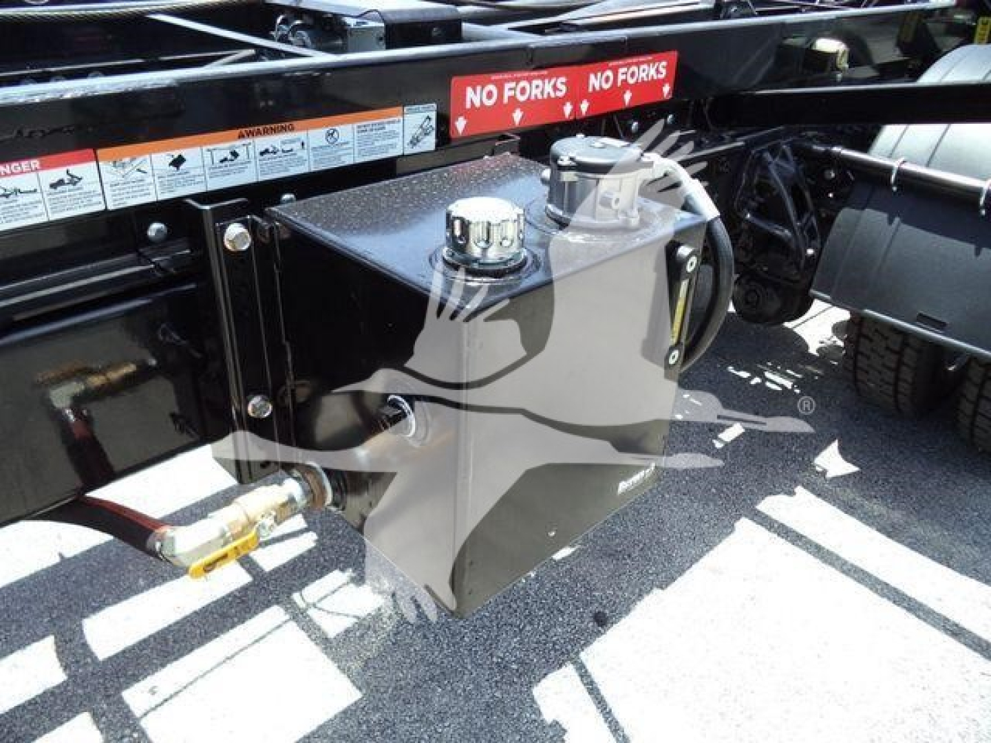 Truck fuel/tank reservoir assembly mounted on Peterbilt chassis with cap and hoses, visible warning stickers and frame rails