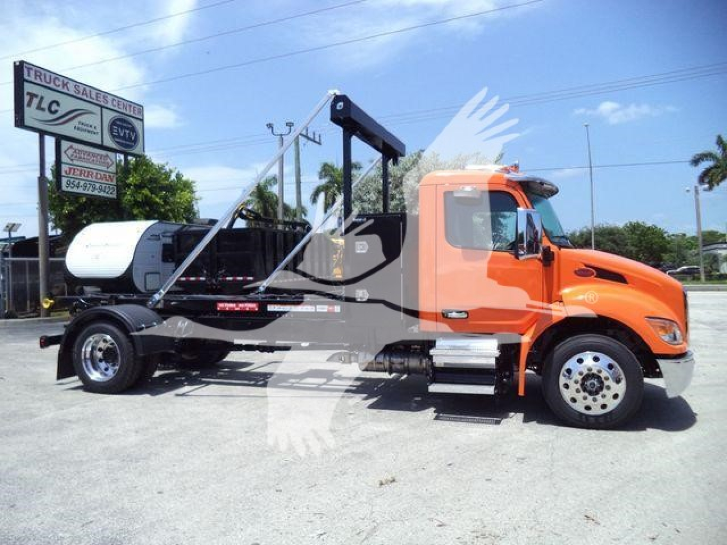 Peterbilt 536 tow truck in orange cab with black chassis and loading crane, visible stock number SNGPETE536 signage in lot.