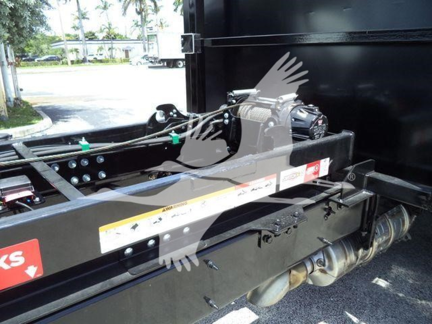 Truck chassis and hydraulic components of a Peterbilt truck bed assembly, black steel frame with hydraulic winch and hose lines visible.