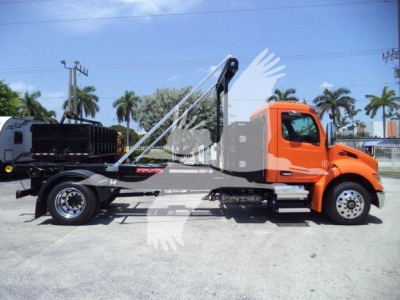 Orange Peterbilt 536 flatbed tow truck with crane arm viewed from side showing chassis and wheelbase