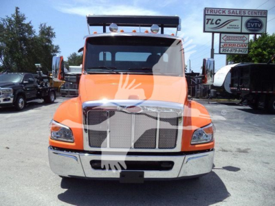 Peterbilt 536 front view in orange with chrome grille and bumper, truck dealership lot in background.