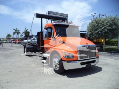 Peterbilt 536 truck in orange color, front view with chrome bumper and grille, parked at dealership lot.