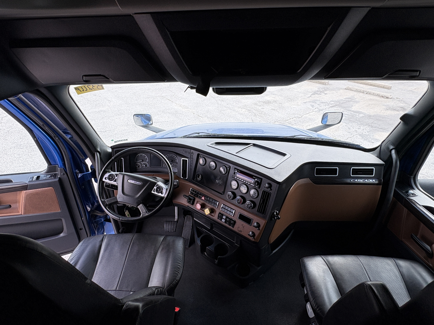 Cabin view of a 2022 Freightliner Cascadia 126 truck showing dashboard, steering wheel, and front seats.