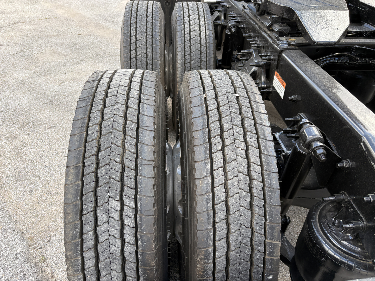 Freightliner Cascadia 126 truck drivetrain showing dual rear tires and suspension components with visible wheel wells and chassis hardware.