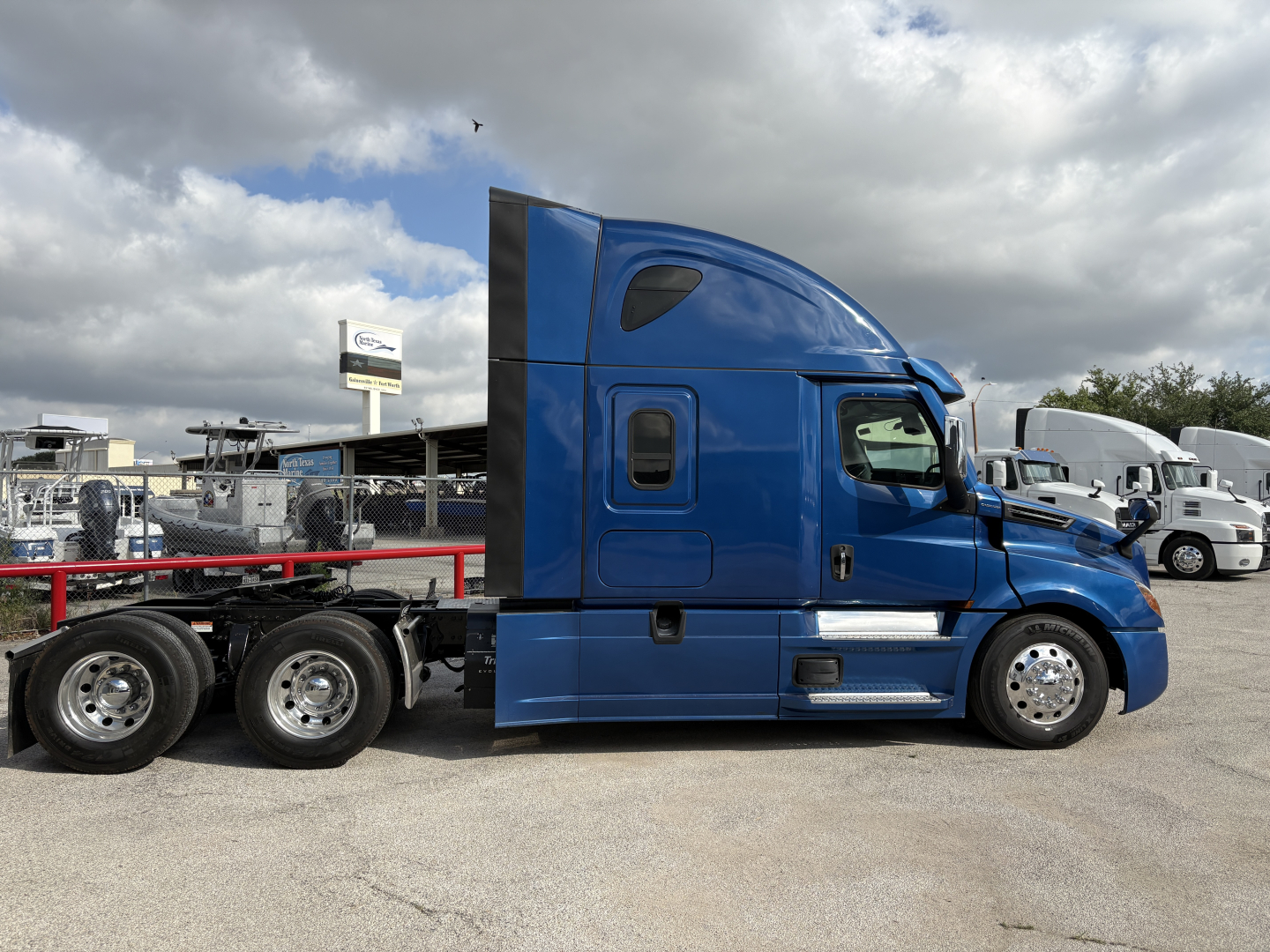 Freightliner Cascadia 126 sleeper tractor side view with blue cab and six wheels on the trailer last five axles.