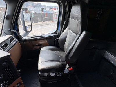 Truck cab interior of a 2022 Freightliner Cascadia 126 showing driver seat and dashboard area.