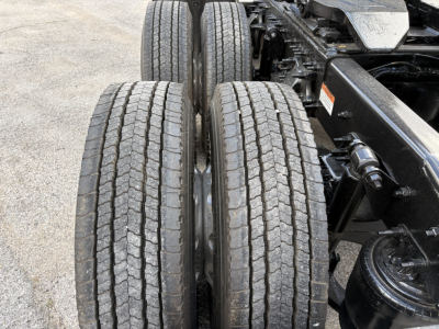 Freightliner Cascadia 126 truck drivetrain showing dual rear tires and suspension components with visible wheel wells and chassis hardware.