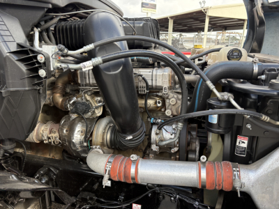 Engine bay of a 2022 Freightliner Cascadia 126 showing intake tubing, turbocharger, hoses, radiator hoses, and engine components.