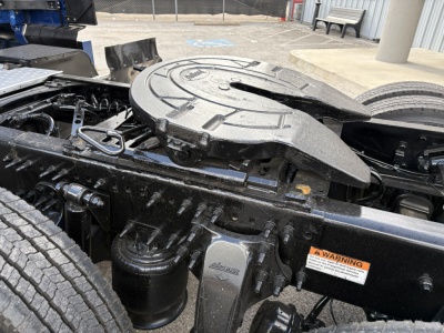 Truck engine bay area of a 2022 Freightliner Cascadia 126 showing a circular fifth-wheel/propane-style power take-off housing and surrounding frame components.