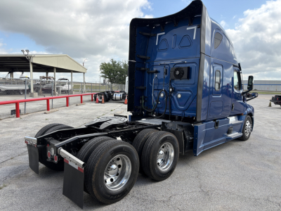Freightliner Cascadia 126 tractor, rear view showing dual rear axle and blue cab, with fifth wheel and chassis components visible.