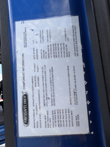 Freightliner component information label on the door frame of a 2022 Freightliner Cascadia 126 showing model, engine and serial details.
