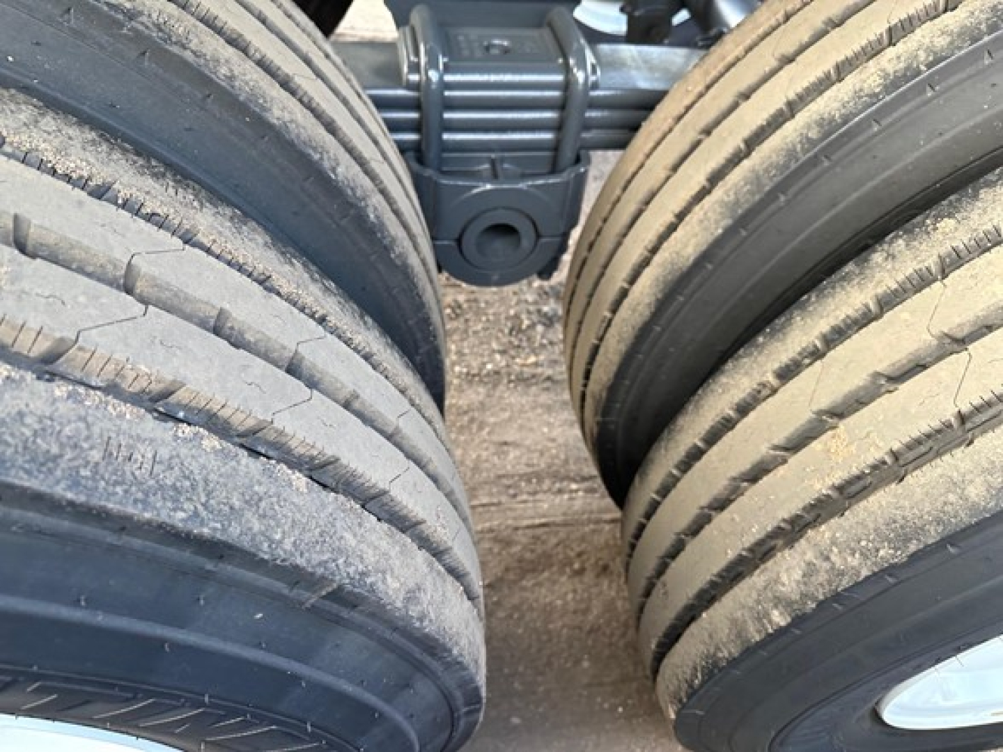 Trailer axle and tires close-up showing two large dual tires with tread lines, part of a heavy-duty dump trailer undercarriage.