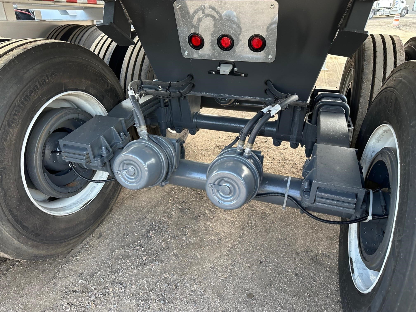 Frameless rock end dump trailer rear axle assembly showing dual pneumatic suspension airbags and differential housings, with wheels and tire treads visible.