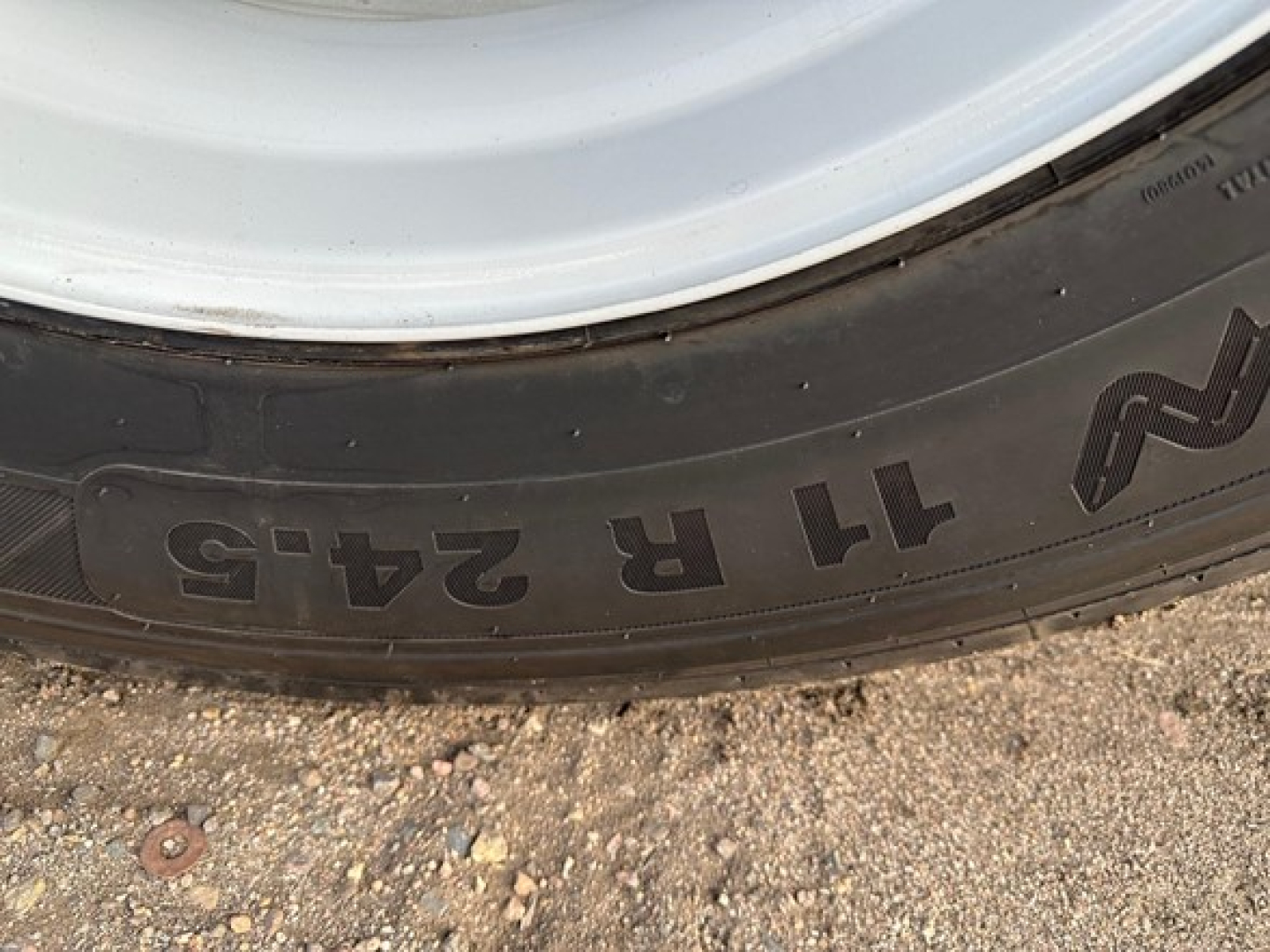 Trailer tire sidewall showing embossed markings '11 R 245' with part of the wheel rim visible.