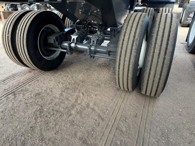 Frametruck trailer landing gear and dual-axle wheels showing suspension and tire treads for a 2026 CPS frameless rock end dump.