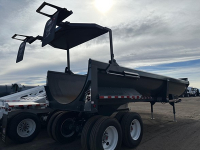 Frameless rock end dump trailer with high lift gate in profile view showing dual rear axles and raised bed