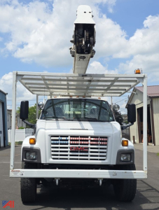 Front view of a 2009 GMC TopKick C7500 utility truck with a mounted boom lift, white cab, large grille, and metal utility frame overhead.