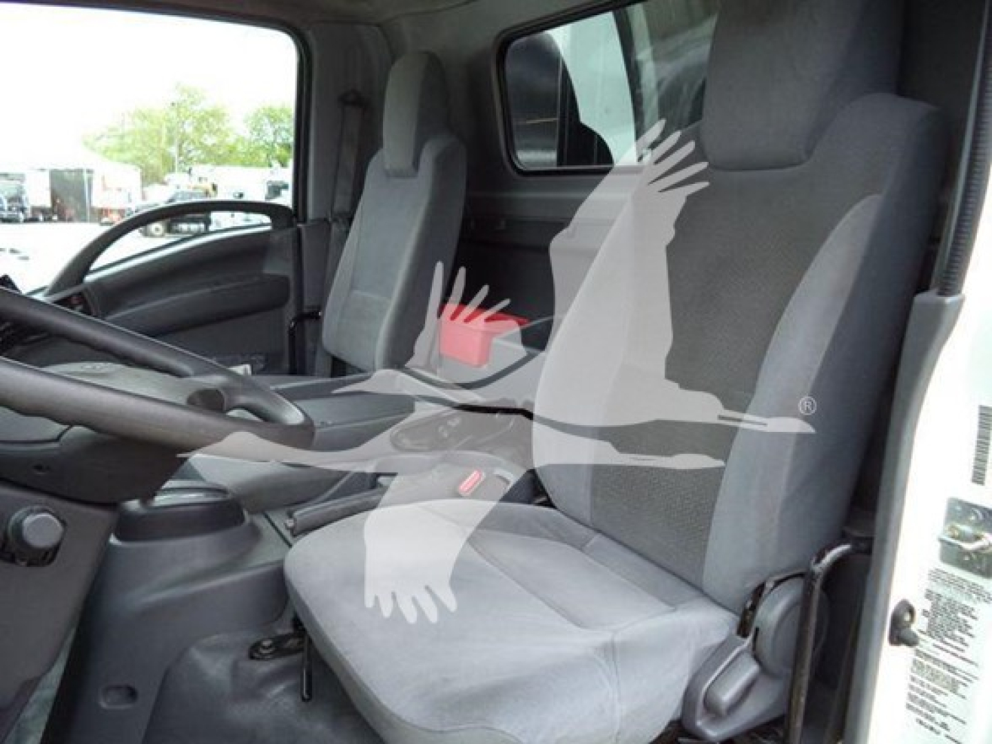 Isuzu NPR truck cabin interior with two front seats and steering wheel, text visible on seat fabric and side panel