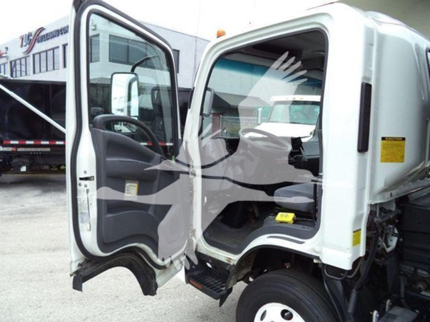 Isuzu NPR truck cab interior and open door showing steering wheel dash and empty passenger seat.