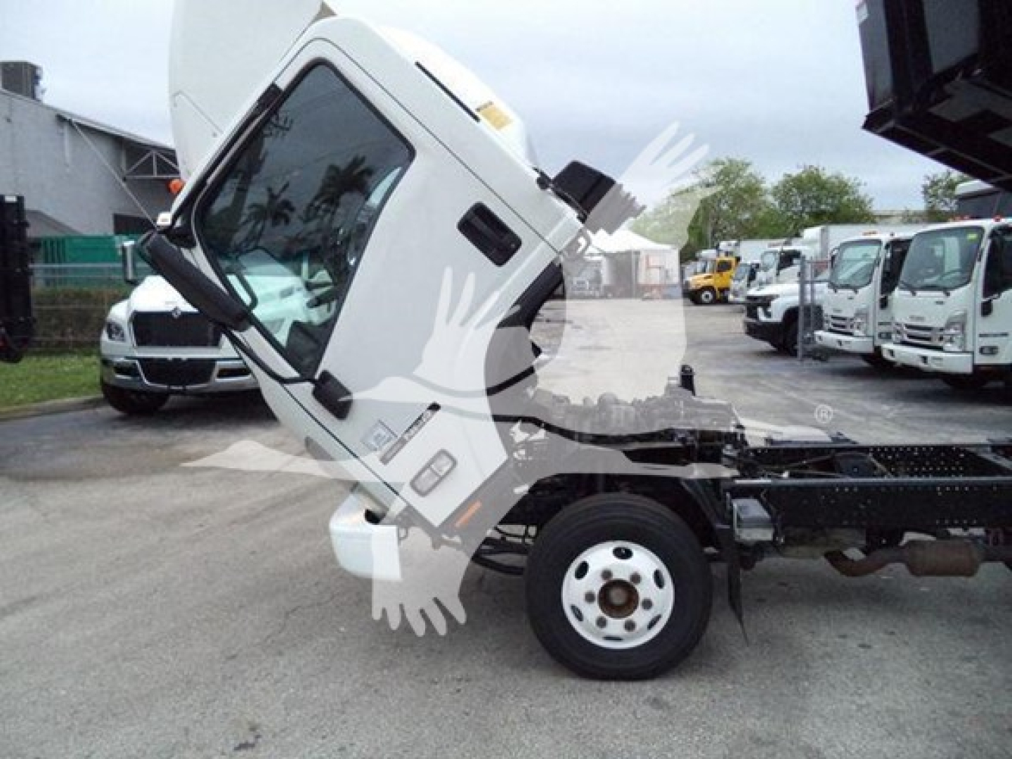 Isuzu NPR truck cab tilted on a dump truck chassis showing side view with front wheel and lifted cab.