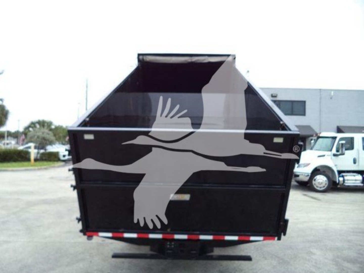 Back view of a black dump truck bed with a white bird decal spanning the tailgate area.