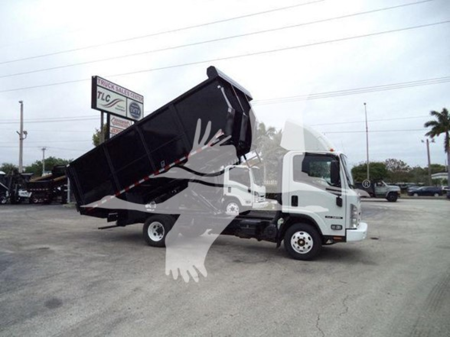 Isuzu NPR dump truck with bed raised, side view showing cargo bed and cab.