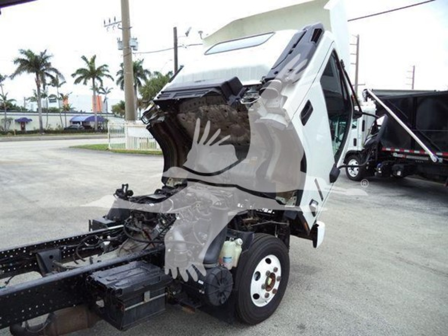 Isuzu NPR truck with cab tilted forward showing engine bay area and front wheel, stock number T04471.