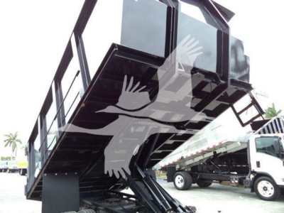 Isuzu NPR dump truck in-service showing dump body raised, side view with hydraulic arms and frame, truck in yard.