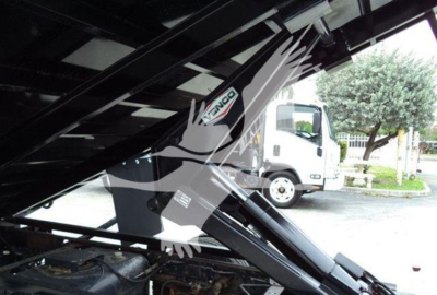 Isuzu NPR truck image showing hydraulic dump mechanism and Isuzu logo on the crane arm. View focuses on underside of dump bed with metal support beams.