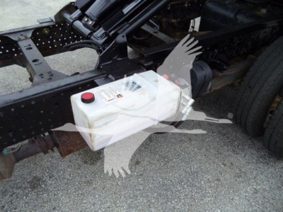 Isuzu NPR truck chassis showing a white rectangular plastic reservoir with a red cap mounted under the frame.