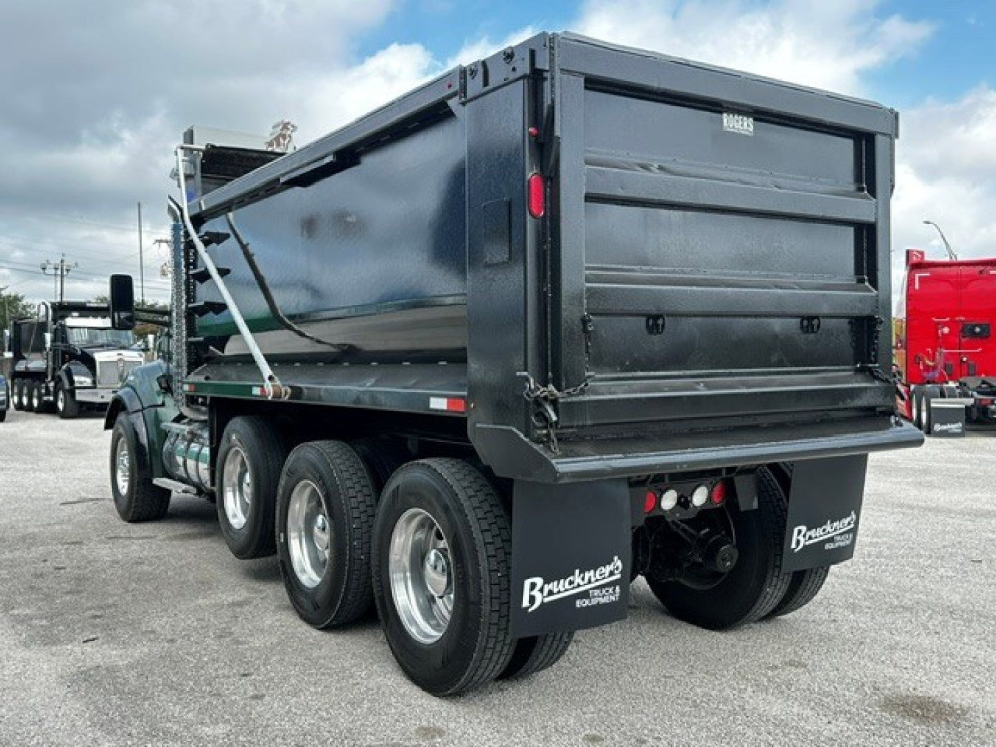 Kenworth T880 dump truck rear and side showing dual rear axles, black dump bed, mud flaps with Bruchner equipment logo, taillights, and rear bumper.