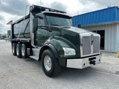 Green 2017 Kenworth T880 dump truck front-three-quarter view with chrome grille, large bumper, and dual rear wheels. Cab-over portion shows emblem text Kenworth.