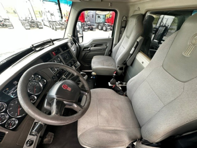 Kenworth T880 truck interior showing steering wheel with Kenworth emblem, front dashboard, and grey cloth seats.