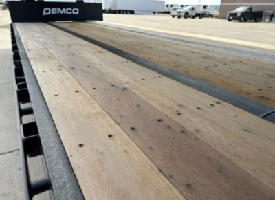 Dropdeck trailer bed showing wooden decking and metal edge with DEMCO branding in the background.