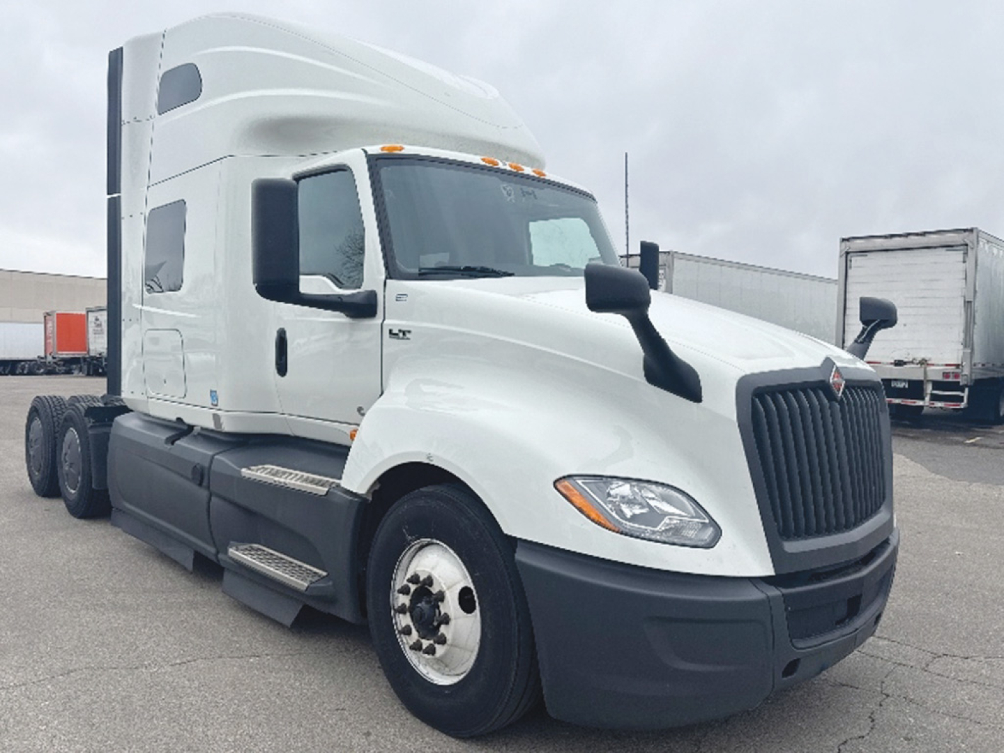 White 2023 International LT625 semi-truck cab shown at angle with sleeper cab, large black grille, side mirrors, and dual rear wheels.