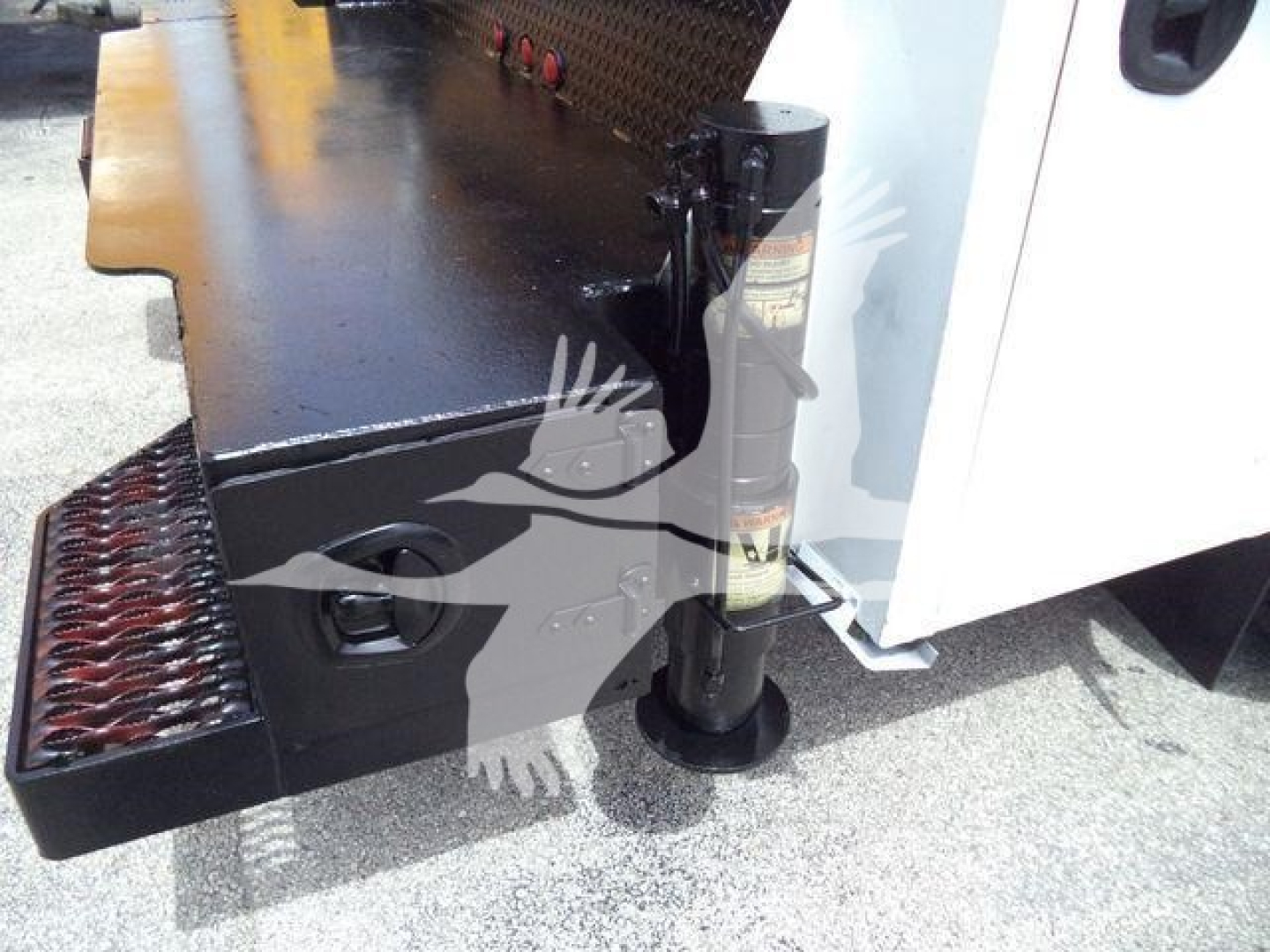 Kenworth T270 service truck rear bumper and stabilizer jack detail showing a black metal step and pedestal jack with a white cab visible.